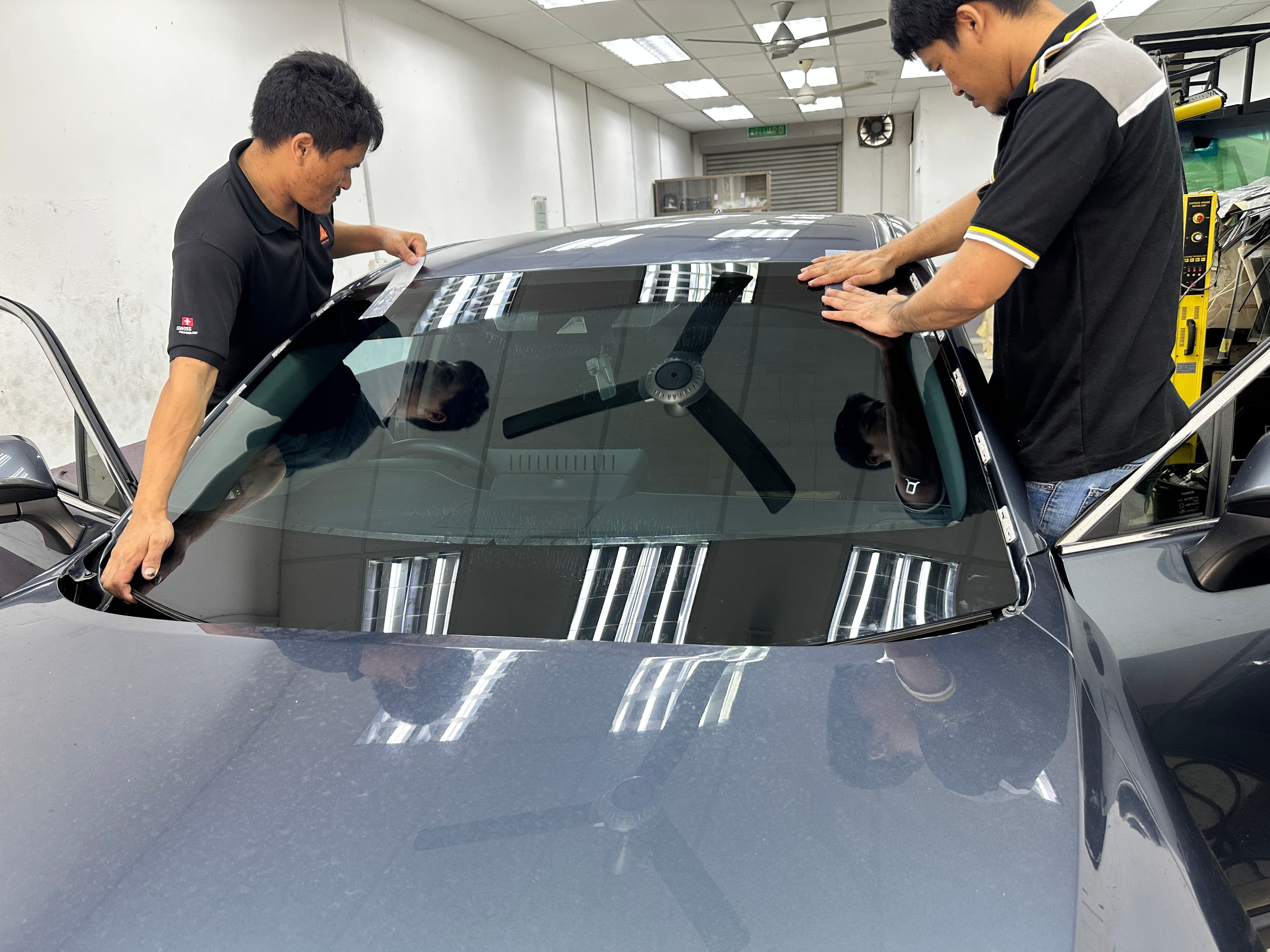 Dua juruteknik memasang windscreen Toyota di bengkel SIFU CERMIN Senawang
