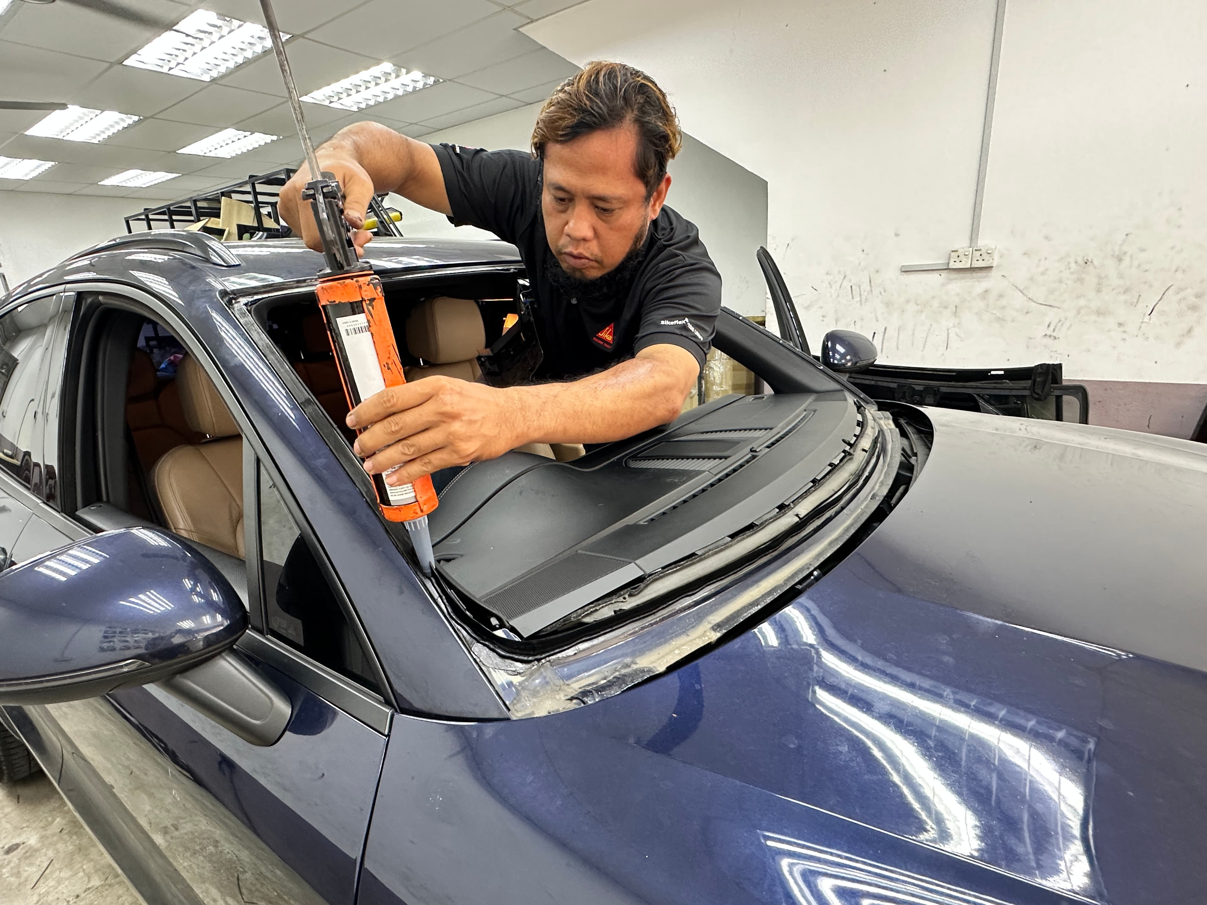 Juruteknik SIFU CERMIN menyapu pelekat pada bingkai windscreen Porsche