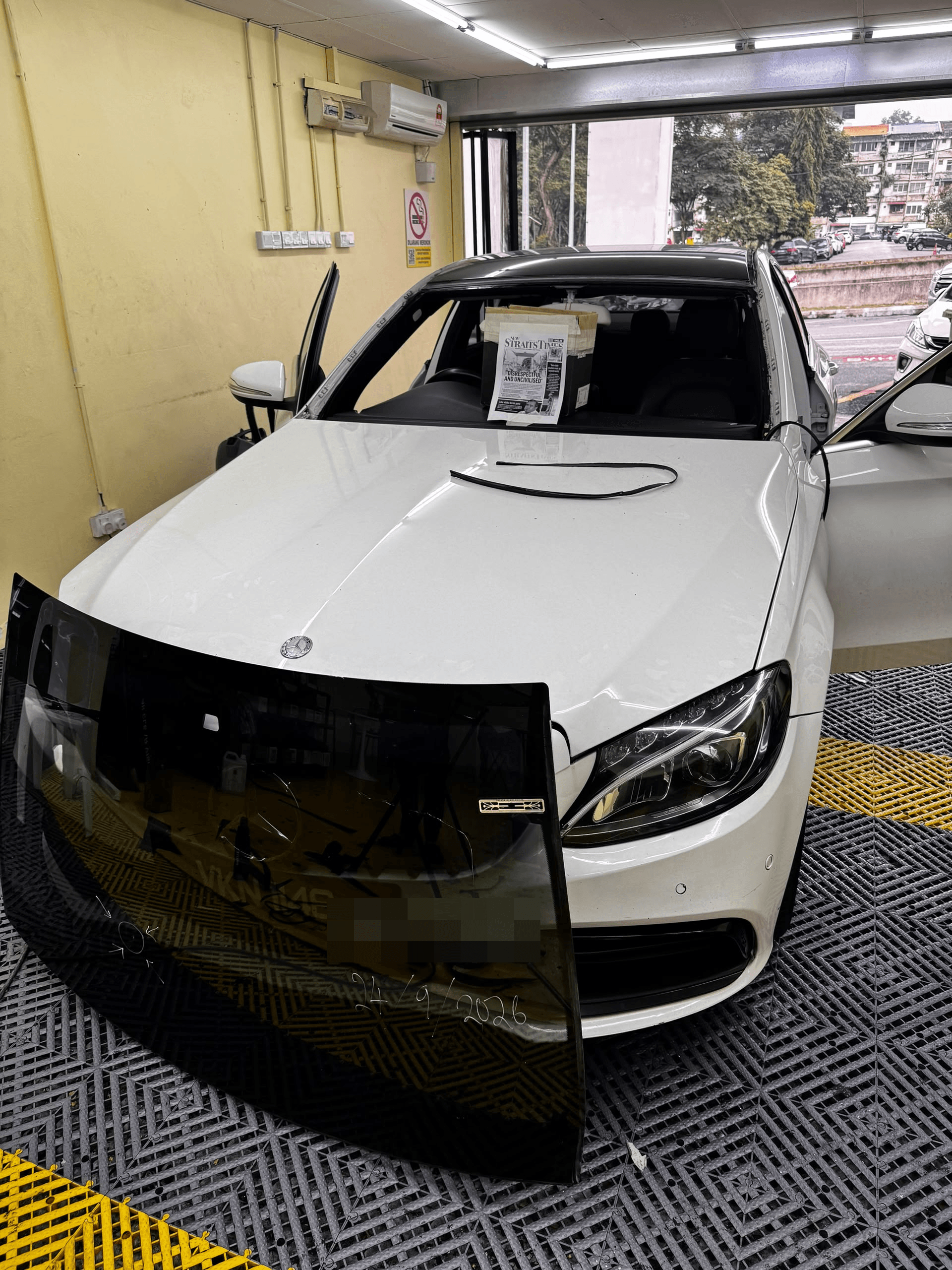 Mercedes putih dengan windscreen dikeluarkan dan kaca lama di hadapan kereta semasa proses penukaran di Cheras.